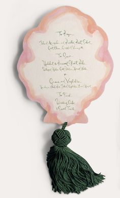 the wedding stationery is decorated with green tassels and pink watercolor paper