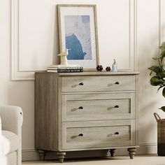 a dresser with drawers in a living room next to a chair and potted plant