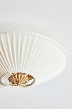 a close up of a white ceiling light with gold trim and fan blades on it