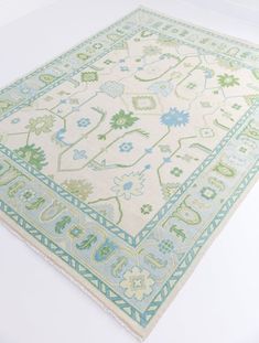 a green and blue area rug on a white floor with an intricate design in the middle