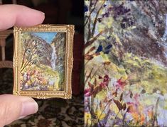 a person holding up a small painting in their hand