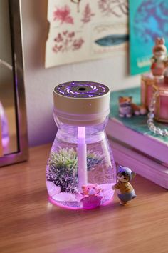 a small figurine sitting on top of a table next to a jar filled with plants