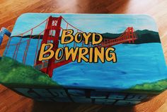 a box with the words boyd bowring painted on it sitting on a wooden floor