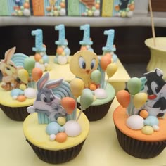 some cupcakes with animals on them sitting on a table