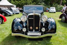 an antique car parked in the grass at a car show with other classic cars behind it