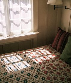 a bed sitting under a window next to a lamp