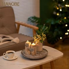 a coffee table with candles on it in front of a christmas tree and a chair