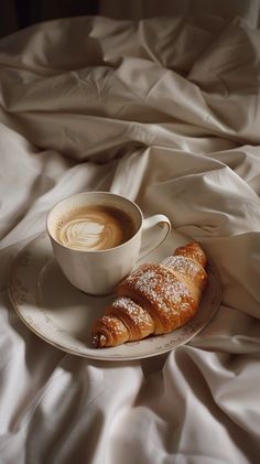 two croissants on a plate with a cup of coffee