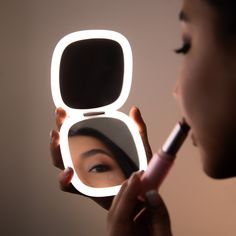 a woman is looking at her reflection in the mirror while she brushes her teeth with an electric toothbrush