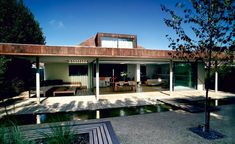 a house that is sitting in the middle of some trees and grass with a patio