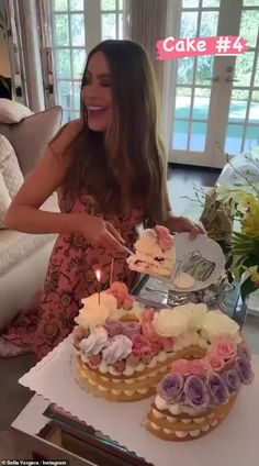 a woman sitting in front of a cake on top of a table with two cupcakes