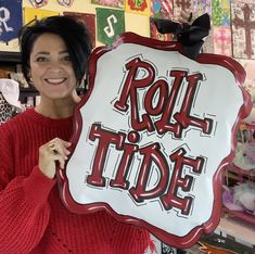 a woman holding up a sign that says roll tide in red and white lettering on it