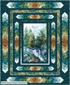 a quilt with a waterfall and trees in the background