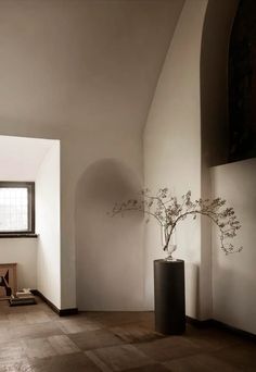 a vase with some flowers in it sitting on the floor next to a chair and window