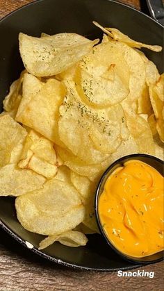 chips and dip in a black bowl on a wooden table