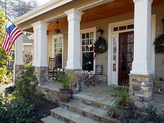 an american flag on the front porch of a house with stone steps and large columns