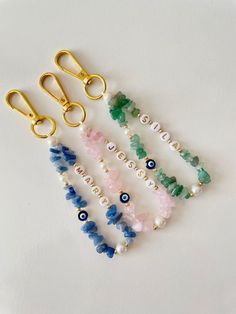 six different colored beads and gold scissors on a white surface