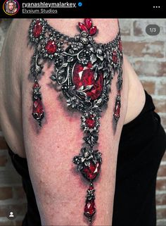 the back of a woman's shoulder with red jewels on it and an ornate design