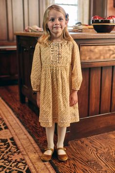 Our Ashley Dress in Golden Floret combines vintage-inspired detailing with modern practicality. This sweet style captures the essence of autumn with its warm shades of yellow and wheat in a hand-painted blend of diamond and block patterns adorned with tiny florals. This versatile silhouette features thoughtful design details, including bracelet sleeves that won’t interfere with her adventures, embroidery at the hem, and button-covered snaps at the front placket. It’s a perfect-for-all-things dre Folk Style Beige Dress With Floral Embroidery, Festive Yellow Embroidered Dress With Floral Details, Baby Prairie Dress, Vintage Beige Cotton Prairie Dress, Toddler Mustard Plaid Dress, Baby Bottoms, Boys Bottoms, Block Patterns, Sweet Style