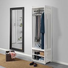 a white coat rack sitting next to a mirror on top of a rug in a room