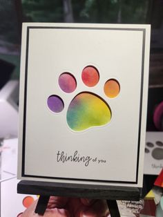 someone holding up a card with an animal's paw painted on the inside of it