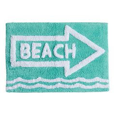 a bath mat with an arrow and the word beach written on it in white ink