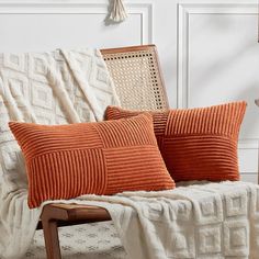 two orange pillows sitting on top of a white couch