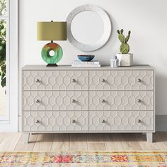 a white dresser sitting next to a wall with a mirror on it's side