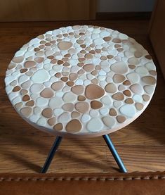 a white table topped with lots of brown and white pebbles on top of a wooden floor