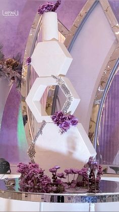 a large white cake sitting on top of a table in front of a round mirror