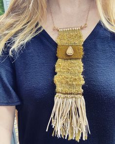 a woman wearing a necklace with fringes and a gold pendant on it's neck