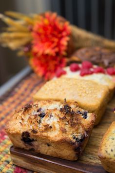 several different types of bread on a cutting board with flowers in the backgroud