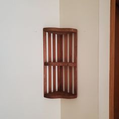 a wooden shelf mounted to the side of a white wall next to a door and window