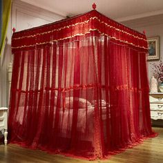 a red canopy bed in a room with hardwood floors