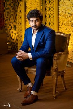 a man in a blue suit sitting on a chair