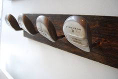 three golf clubs are mounted on a wooden rack