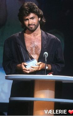 a man standing at a podium with an award in his hand and looking off to the side