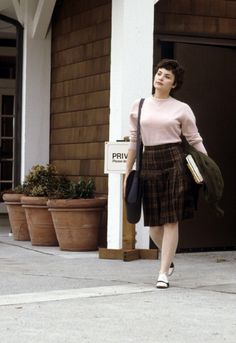 a woman walking down the sidewalk in front of a building