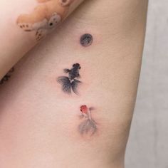 a small tattoo on the side of a woman's stomach shows two fish and a bear