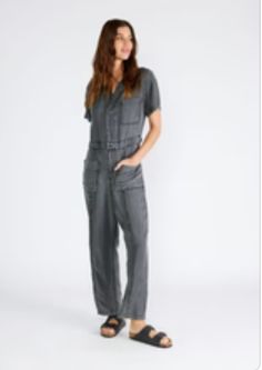 A classic utility-style jumpsuit in an ash grey wash tencel. Tencel Relaxed fit Short sleeve Long straight leg Collared neckline Button front top Zip fly closure Front patch pockets Back patch pocket Utility jumpsuit A jumpsuit to wear on repeat all spring and summer long. Featuring the perfect relaxed fit, our utility-style one-piece is crafted from lightweight tencel and features a button-front top and collared neckline. Short sleeves keep things breezy, while the straight long leg pairs well Utility Style Denim Jumpsuit With Short Sleeves For Work, Short Sleeve Denim Utility Jumpsuit For Workwear, Utility Washed Overalls Jumpsuit, Utility Style Jumpsuits And Rompers With Button Closure, Gray Jumpsuits And Rompers With Pockets For Spring, Gray Spring Jumpsuits And Rompers With Pockets, Fall Jumpsuits And Rompers With Pockets And Short Sleeve, Casual Washed Black Denim Jumpsuit With Pockets, Casual Washed Black Jumpsuits And Rompers With Pockets