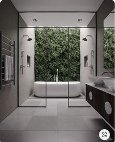 a bathroom with two sinks and a bathtub in front of a wall of plants