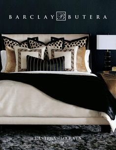 a bed with black and gold pillows on it in a room that has dark walls