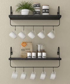 two black shelves with cups and coffee mugs on them, one shelf is hanging from the wall