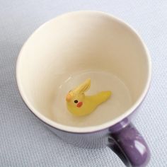 a small yellow bird sitting in a white cup