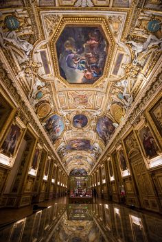 an ornate ceiling with paintings on it in the middle of a room filled with marble flooring