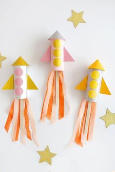 three rockets made out of construction paper on top of a white surface with stars around them