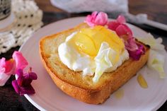 a piece of bread topped with whipped cream and flowers on a plate next to a cup