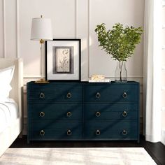 a bedroom with a blue dresser next to a white bed and framed pictures on the wall