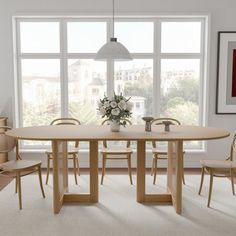 a dining room table with four chairs and a vase on the table in front of a large window