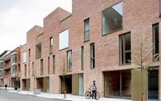 a man riding a bike down a street next to tall brick buildings on both sides